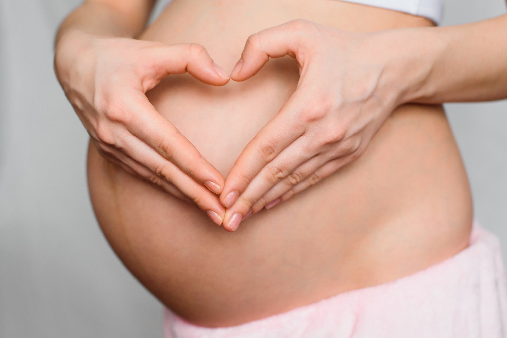 Pregnant Woman Making Heart Hand Gesture on Her Belly